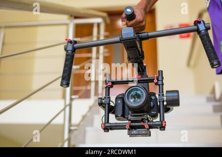 Hand Carrying gimbal camera stabilizer on stairs Hands typing laptop buttons computer technology Stock Photo