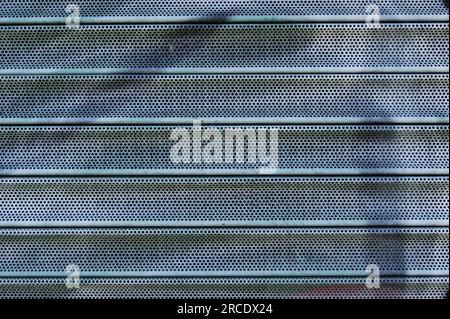 Background of blue horizontal metal strips with blue paint. Roller blinds and garage gates. Closed metal shutter casements close-up. Stock Photo