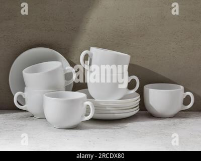 A set of white ceramic dishes on the table, cups and saucers for tea or coffee Stock Photo