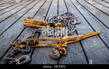 Two old, used and rusty tie down chains and binders, used to secure an object in place on a flatbed trailer, when transporting cargo from place to pla Stock Photo