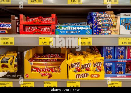 Italy - 13 July 2023: packages of KitKat and Bounty  candy, Smarties and M and Ms Peanut candy and Bisco displayed in branded cardboard boxs on sale o Stock Photo