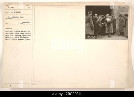 President Wilson is shown receiving a Christmas token from French boys after inspecting the billets of the 26th Division in Sarrey, Haute Marne, France. The photograph was taken on December 25, 1918, by Sgt. Abbott, S.C. It is noted with the symbol E.H. and received the number 36,805. Stock Photo