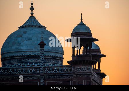 A telephoto shot of Domes atop the Jama Masjid Mosque as the rising sun turns the sky orange Stock Photo