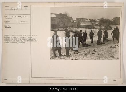 American soldiers from the 8th Field Signal Battalion of the 4th Division are pictured enjoying some leisure time with German children on the ice. The photo was taken in Bad Mullenback, Rhine Province, Germany on January 25, 1919. This image is cataloged under Subject 4-1449 and was taken by Sergeant Lel C. E. Dunn, S.C. (363-F9) with the description '19 Sued Number.' Additional notes include the notation '5190L.' Stock Photo