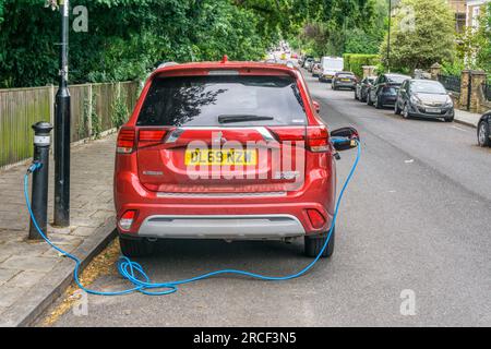 Mitsubishi Outlander PHEV plug-in hybrid car recharging across the kerb from a Ubitricity & Siemens SimpleSocket bollard in a residential street. Stock Photo