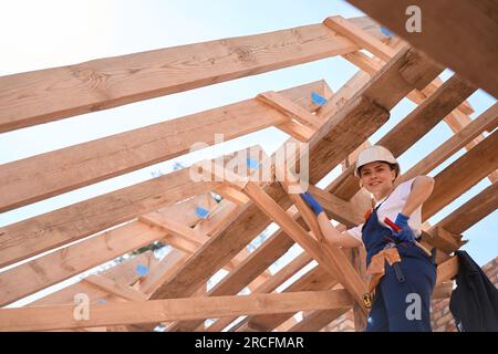 Confident woman builder checking quality of wooden roof construction Stock Photo