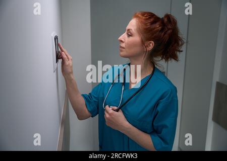 Doctor standing near the wall-mounted device in hospital Stock Photo