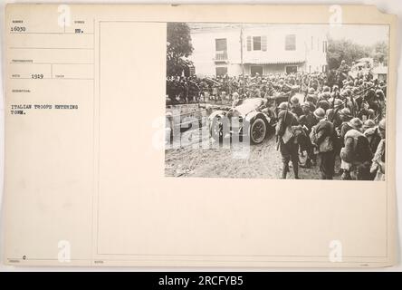 Italian troops entering a town during World War One. The photograph, taken in 1919, shows a group of soldiers marching through the streets, marked by the symbol 'BU'. This image is part of the Photographs of American Military Activities collection, with identifier number 16030. EDC notes indicate that the photograph was taken by RECO in 1919. Stock Photo