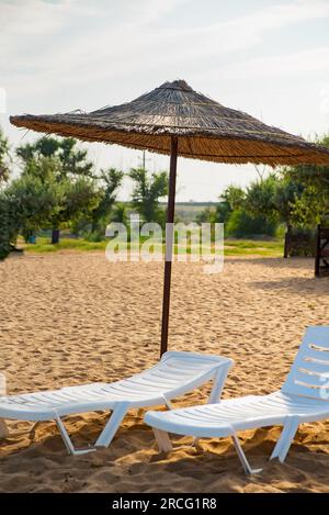 Pair of sun loungers and a beach umbrella on a deserted beach perfect vacation concept Stock Photo