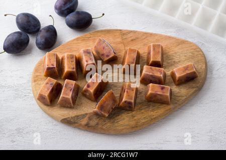 Frozen plum puree and fresh plum on a light gray background. Stock Photo