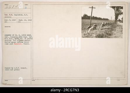 Soldiers from Company B, 165th Regiment Infantry, formerly known as the 69th Regiment Infantry, New York National Guard, 42nd Division, await a patrol assignment near Hazavant, France. The photograph shows them gathered next to a narrow gauge railway. The image was reviewed and approved by the American Expeditionary Forces censor. Stock Photo