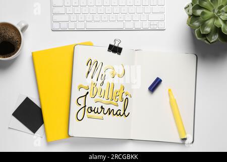Improve your productivity. Notebook with words My bullet journal, keyboard, plant and cup of coffee on white table, flat lay Stock Photo
