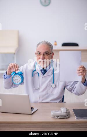 Old doctor in time management concept Stock Photo