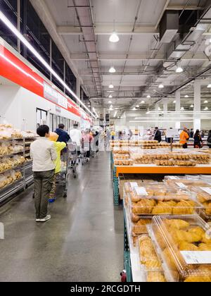 Auckland, New Zealand - June 30, 2023: Customers lining up inside Costco to purchase cooked rotisserie chickens. Stock Photo