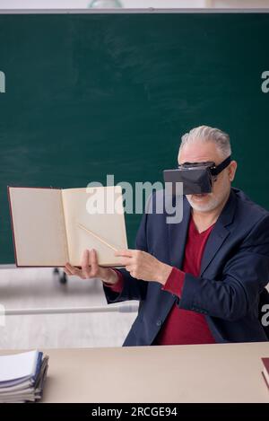 Old teacher wearing virtual glasses in the classroom Stock Photo