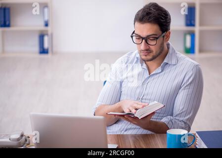 Young businessman employee reading book at workplace Stock Photo
