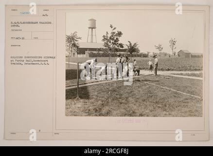 Soldiers from the Mooseheart Training Detachment were photographed constructing a sidewalk at Purity Hall during World War One. The image was taken by Signal Corps photographer S.A.T. C. and is numbered 58985. The soldiers are seen working on the sidewalk, which was part of their training activities. Stock Photo