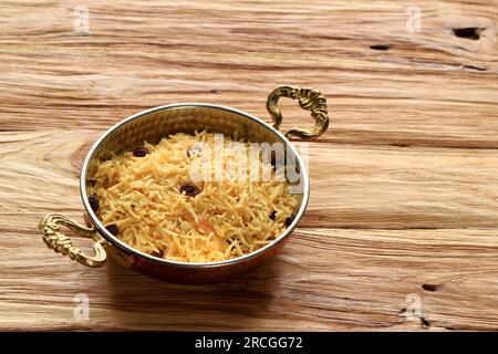 Indian Basmati Coloured Yellow Rice with Raisins on Wooden Table Stock Photo