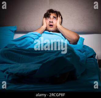 The young man scared in his bed having nightmares Stock Photo