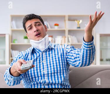 Man with a head neck spine trauma wearing a neck brace cervical collar watching tv at home Stock Photo