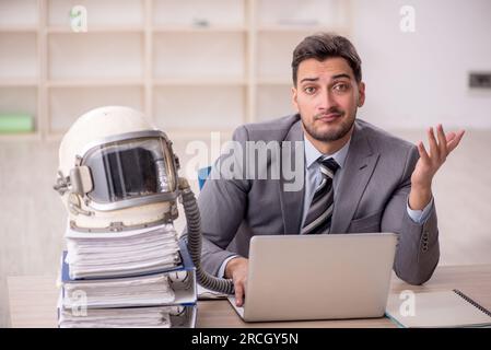 Young businessman employee wearing spacesuit at workplace Stock Photo