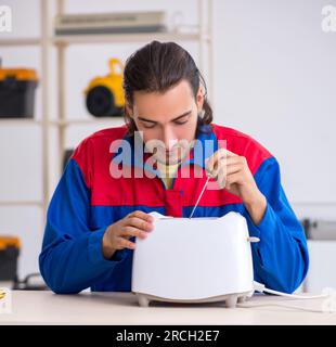 The young male contractor repairing toaster at workshop Stock Photo