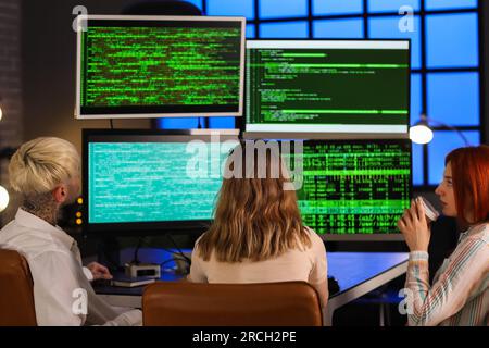 Team of young programmers working in office at night, back view Stock Photo