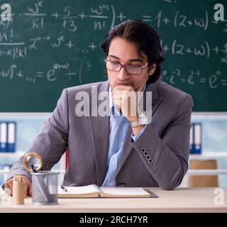 The young handsome math teacher in classroom Stock Photo