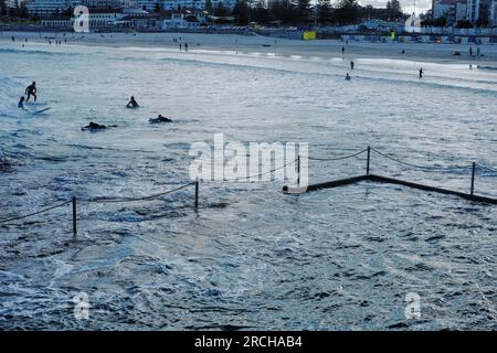 Five surfers silhouetted against the water. Afternoon, surfing at North Bondi, looking out across Wally Weekes Pool back toward the  beach Stock Photo