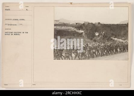 American soldiers marching through a French town during World War One. The streets are lined with onlookers as the soldiers make their way through the urban environment. The soldiers are dressed in military uniforms, carrying rifles and wearing backpacks. Stock Photo