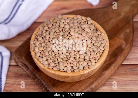 Green lentils on wood background. Raw green lentils in wooden bowl Stock Photo