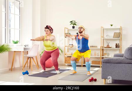 Funny family couple doing squat exercises together at home Stock Photo