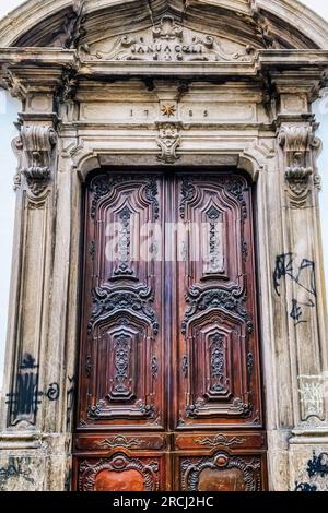Rio de Janeiro, Brazil - June 15, 2023: Ancient door and stone wall in a colonial building. The wooden structure is decorated with carvings. Stock Photo