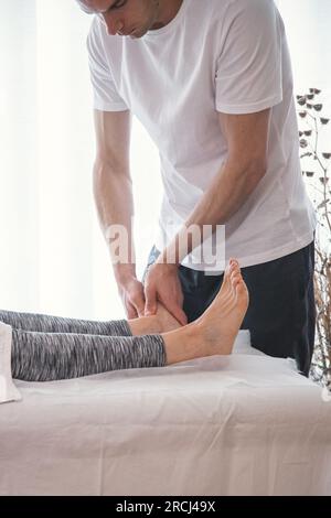 Woman being treated by therapist. Therapist doing pressure and massage exercises through the feet to improve the overall health of the patient. Stock Photo
