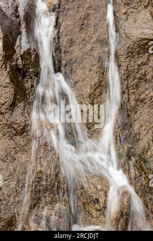 Free falling water cascades down a mountain waterfall Stock Photo