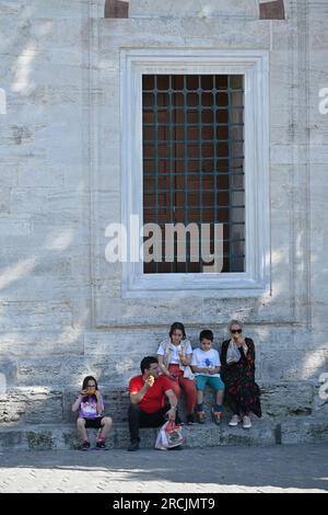 Turkish family sitting and eating outdoor next to an old wall in Sultanahmet area in Istanbul, Turkey Turkish family sitting and eating outdoor next to an old wall in Sultanahmet area in Istanbul, Turkey