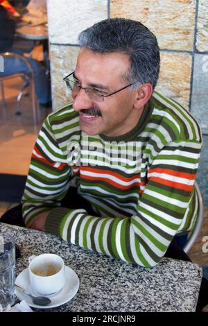 smiling arab man casual dressed relaxing after work having a coffee on a terrace Stock Photo