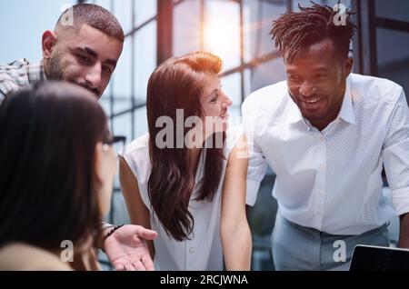 Happy young female worker discussing online project, showing presentation to experienced team leader in glasses. Stock Photo