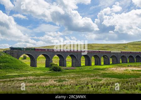 DandryMire Viaduct outside Garsdale with the 'Flying Scotsman' bringing along the carriages behind it over the viaduct on a sunny July day from Settle Stock Photo