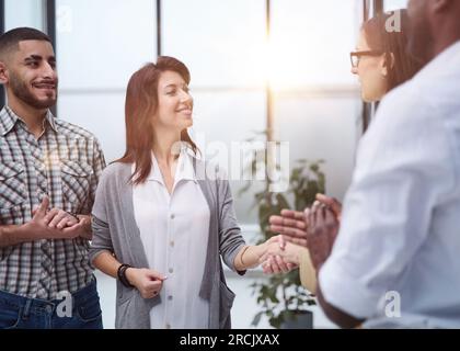 Business people standing and shaking hands in an office building Stock Photo