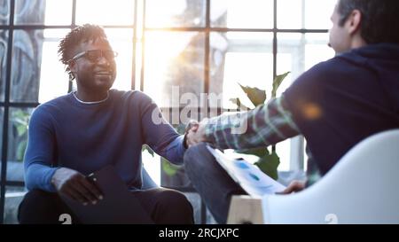 a black man with a folder in his hands shakes hands Stock Photo
