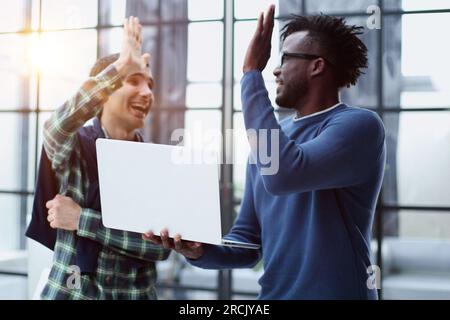 Happy multicultural programmers giving high five while working in office togethe Stock Photo