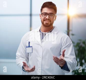 The doctor, an average man, makes a hand gesture inviting patients. Stock Photo