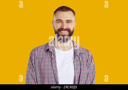 Portrait of happy smiling brunet man in red plaid shirt on yellow background looking at camera. Stock Photo