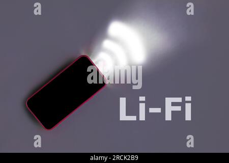Red Smartphone on a gray studio background with light Emitting data. Li-Fi wireless communication concept. Light-Fidelity. W-Lan technology, internet Stock Photo