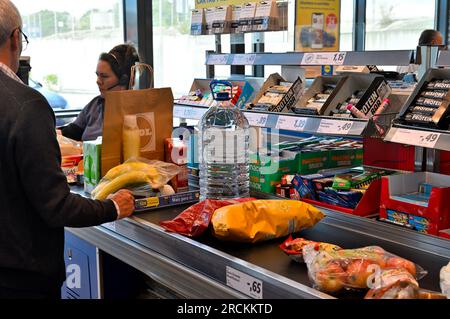 Customer with food on conveyor belt at checkout in supermarket with cashier Stock Photo