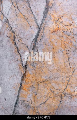 The marble surface with a pink-brown tint is covered with black cracks and spots. Vertical image. Stock Photo