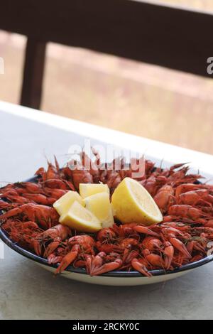 Boiled crayfish. Arranged on a large platter. Garnished with lemon slices. Close-up. Stock Photo