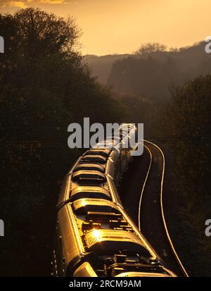 First Great Western railway Hitachi IET bi - mode train heading into the sunset on the south Wales mainline at Llangewydd curving around an s bend Stock Photo