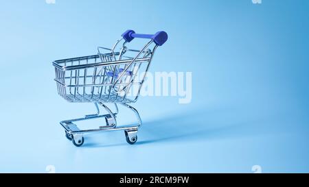 Empty shopping basket or grocery cart on blue with shadow. Stock Photo